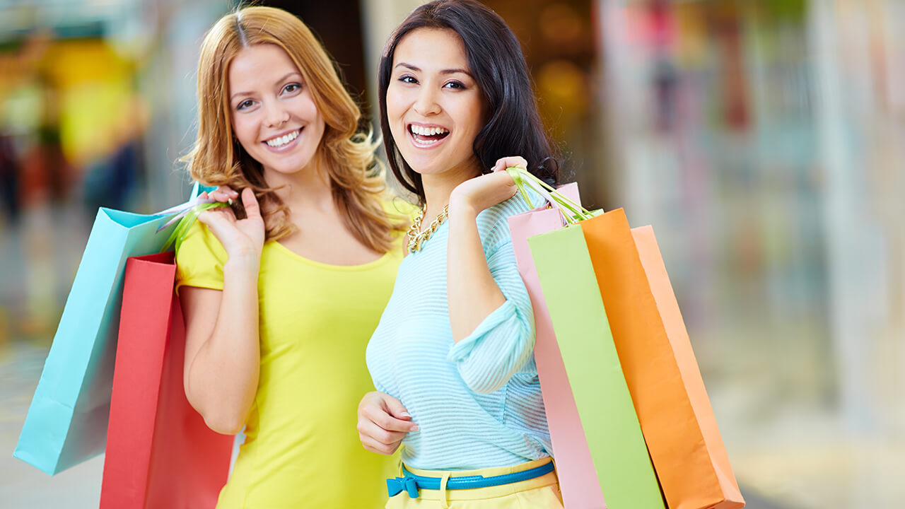 duas jovens clientes carregando sacolas e satisfeitas, fruto de uma estratégia de retenção de clientes
