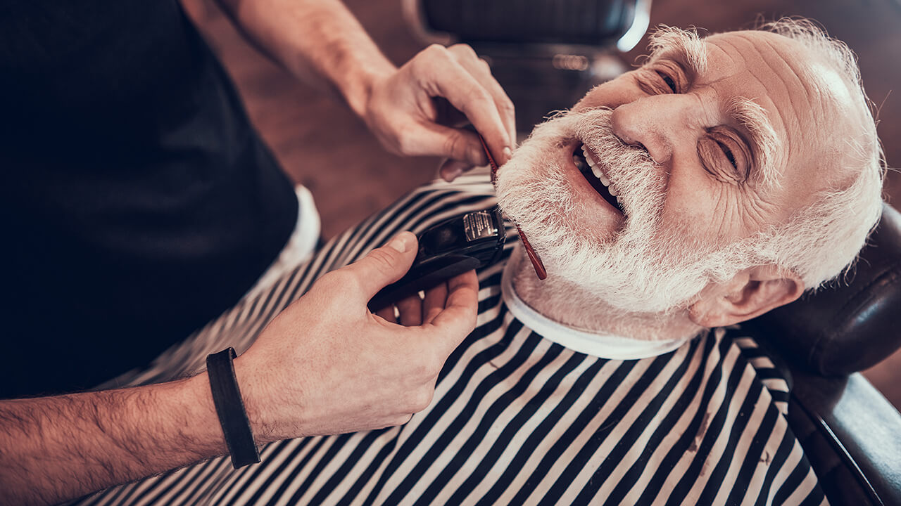 Um senhor, cliente fiel e satisfeito de uma barbearia que aplica estratégias de retenção de clientes