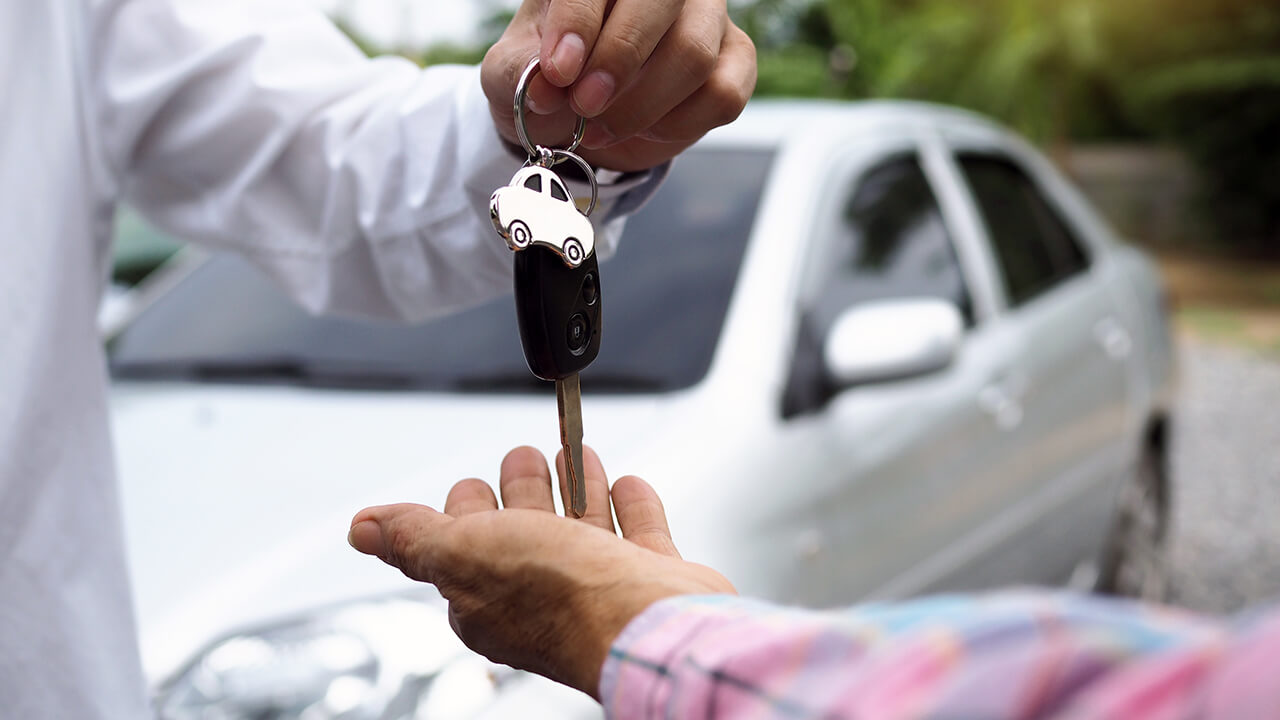 Vendedor entregando a chave do carro para o cliente após uma abordagem de vendas com gatilhos mentais